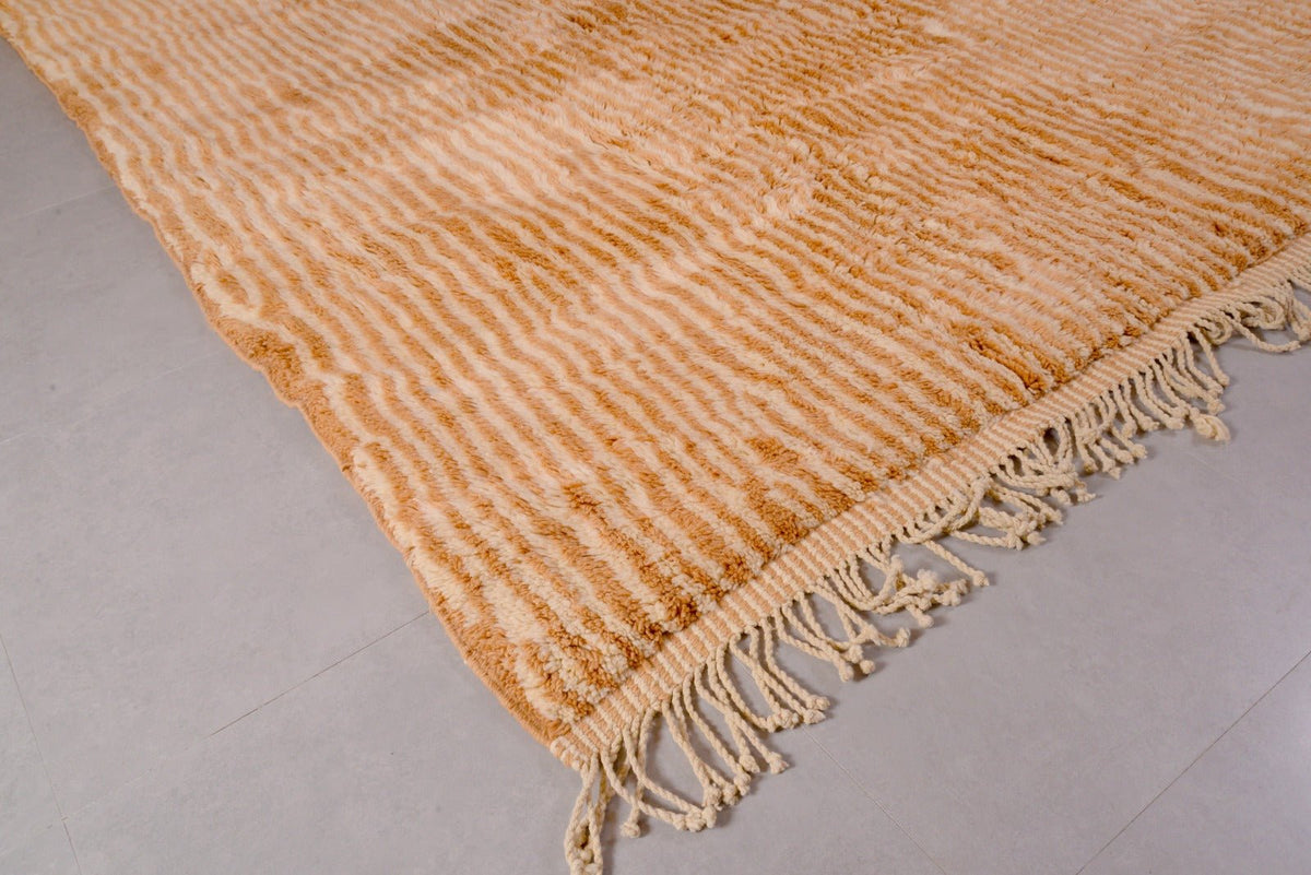 Detail close-up of an orange and beige Moroccan Mrirt rug with a soft texture and fringe edges.