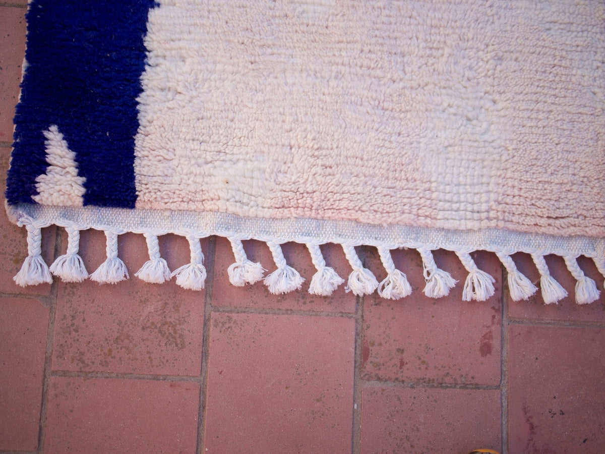 Detail shot of the edge of the pink Moroccan rug featuring fringe detail.