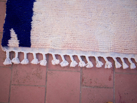 Detail shot of the edge of the pink Moroccan rug featuring fringe detail.