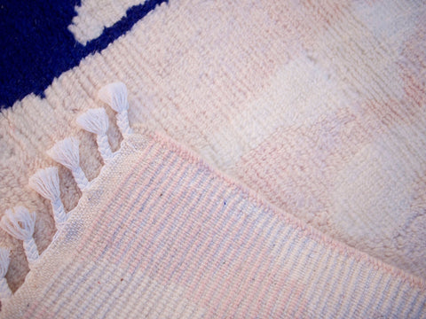Close-up of the textured surface of the soft pink rug with visible fibers.
