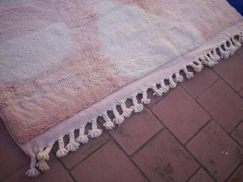 Close-up detail of a pink Beni Ourain rug with fringe edges and soft texture.