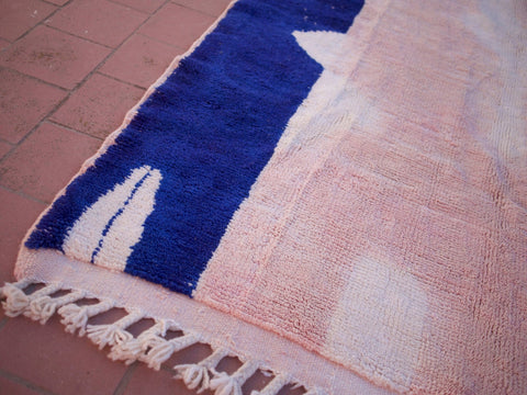 Close-up detail of a pink Beni Ourain rug featuring fringe edges and a soft texture.