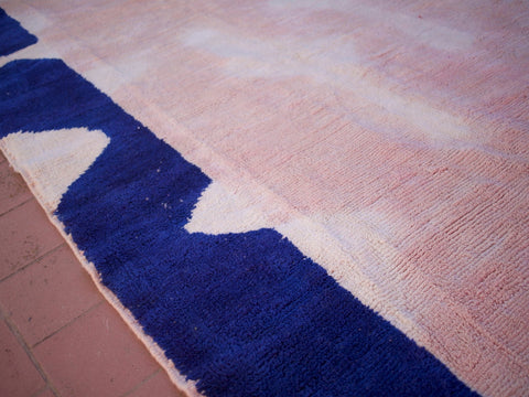 Close-up detail of a pink Beni Ourain rug highlighting its textured surface and abstract shapes.