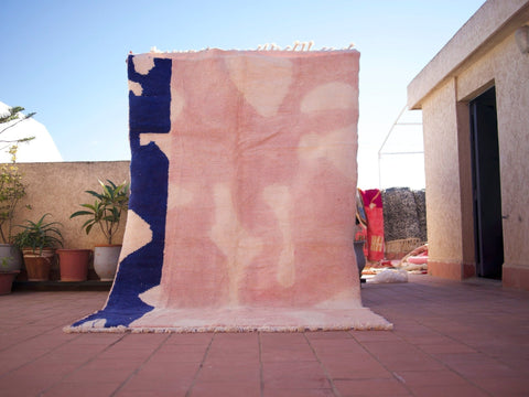 Lifestyle shot of a pink Beni Ourain rug featuring a geometric pattern in a natural setting.