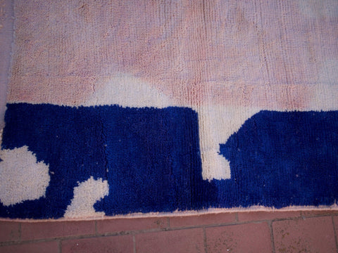 Close-up detail of a pink Beni Ourain rug with contrasting colors and soft fabric in a natural setting.