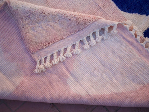 Close-up detail of a pink Beni Ourain rug showcasing fringe edges and soft texture.