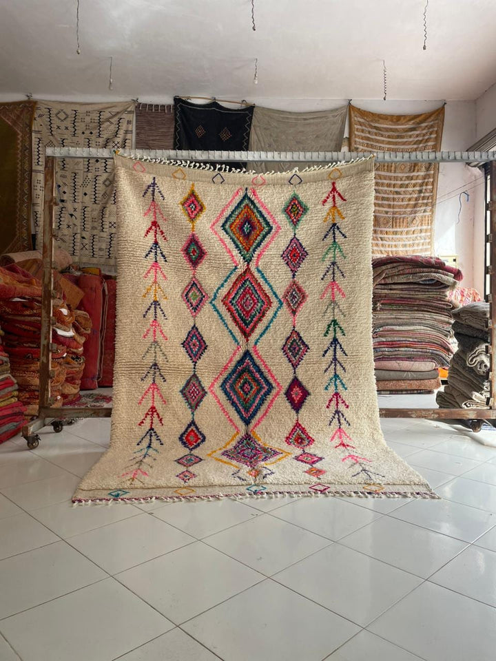Lifestyle shot of a colorful vintage Moroccan rug featuring geometric patterns in cream, red, blue, and purple.