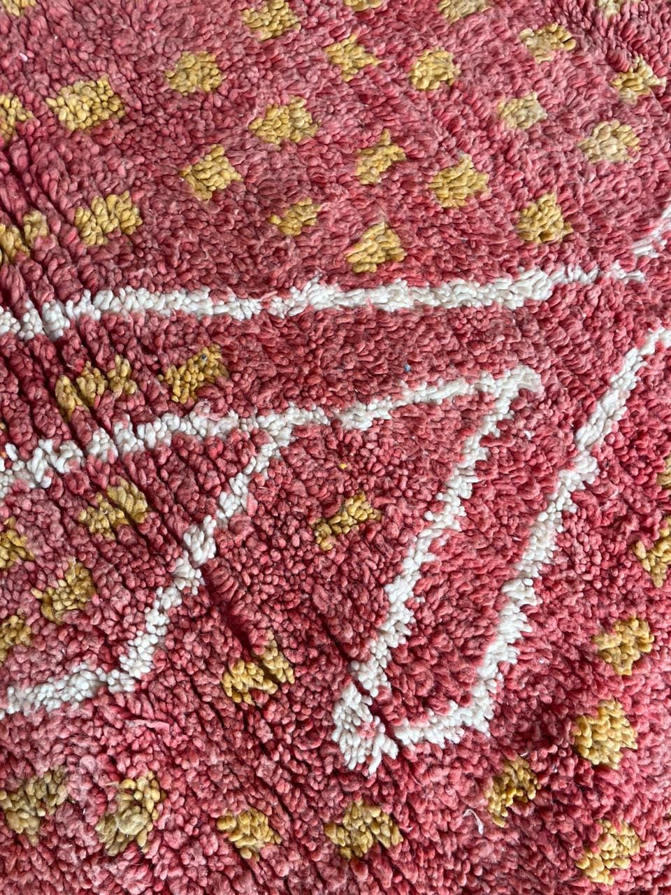 Detail shot of bold lines and decorative motifs on a vintage Moroccan rug in red, white, and yellow.
