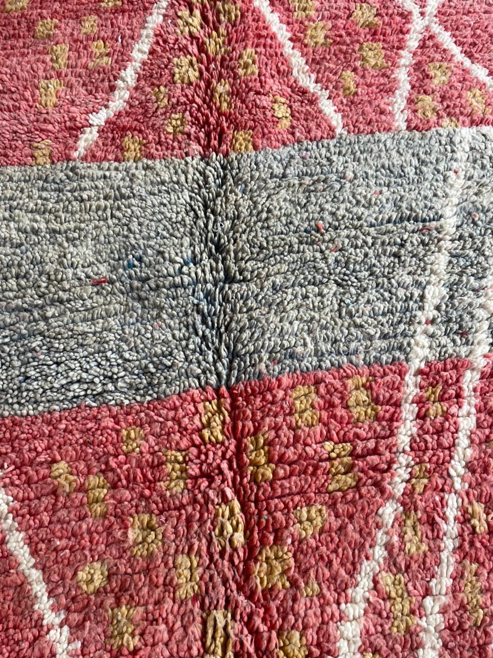 Close-up detail of the intricate design and textured fabric of a vintage Moroccan rug in red and gold.