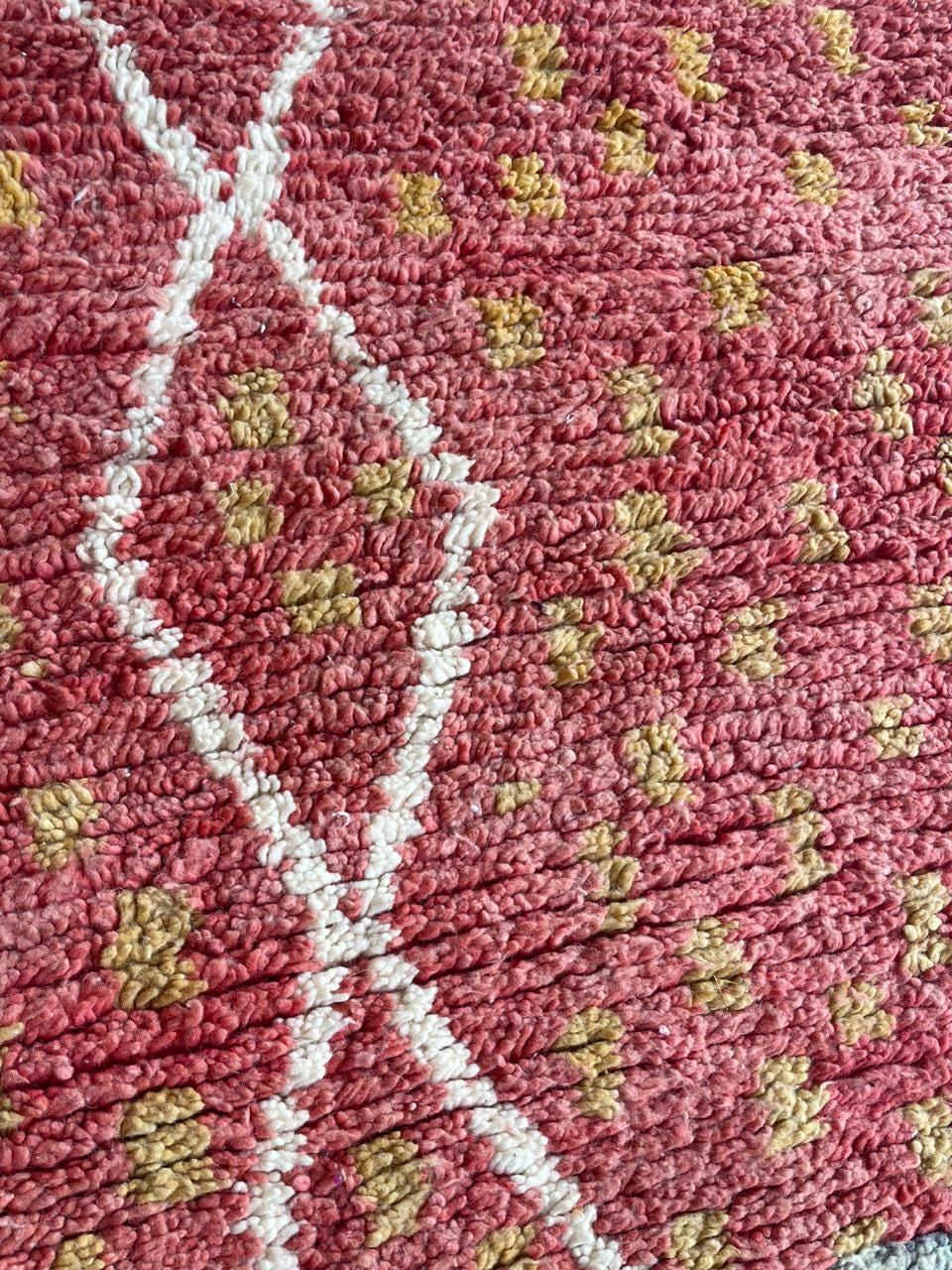 Detail shot of a vintage Moroccan rug pattern with geometric motifs in red and yellow.