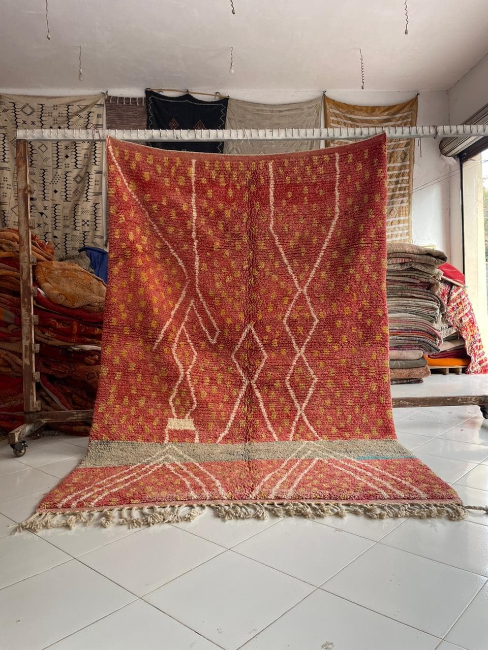 Lifestyle shot of a vintage Moroccan rug featuring red and cream colors with fringe edges.