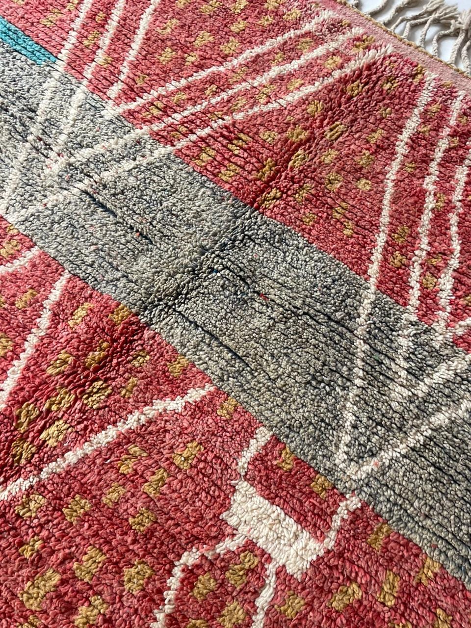 Close-up detail of the textured surface of a vintage Moroccan rug in red and gray.