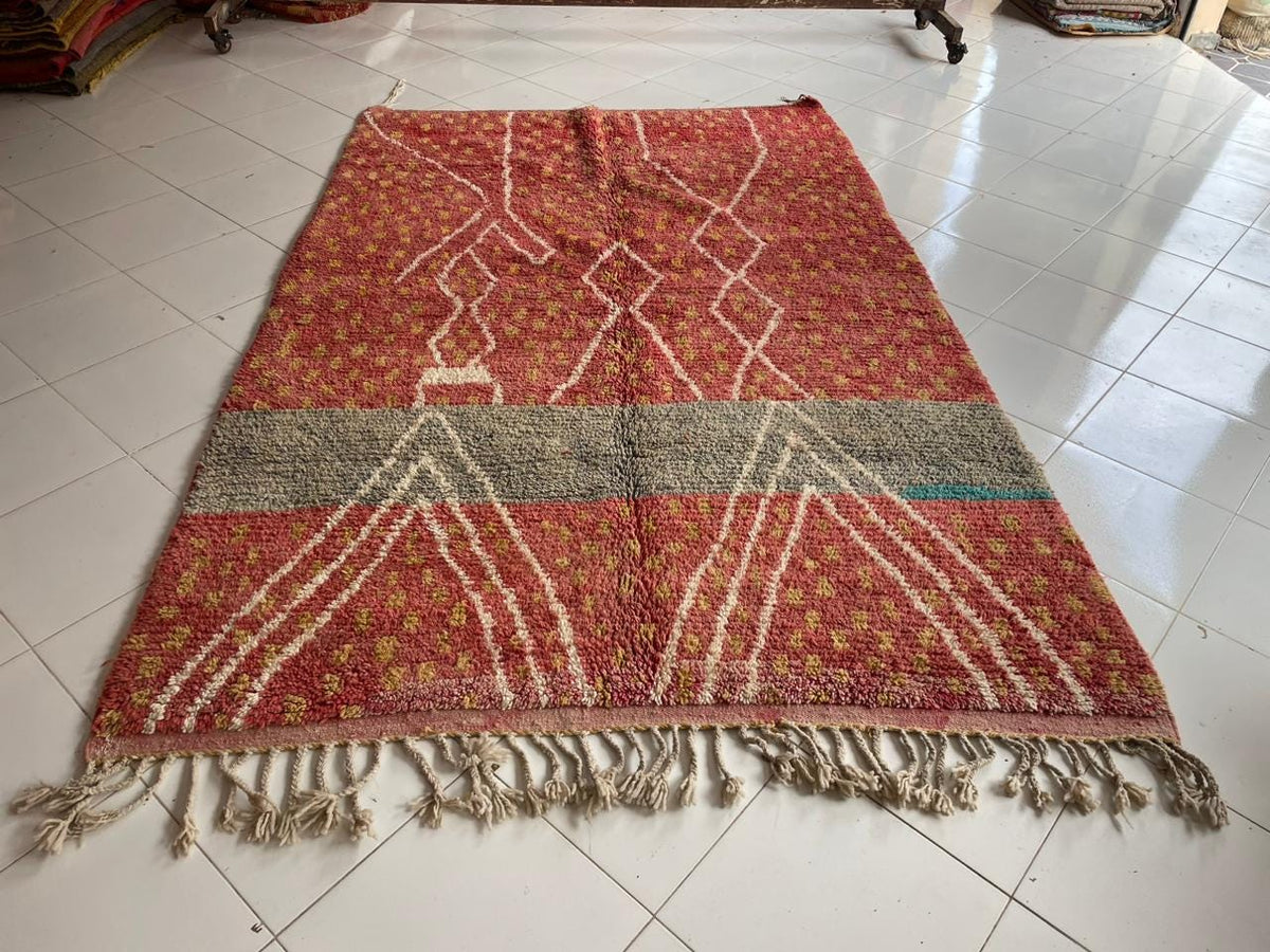 Top view of a vintage Moroccan rug showcasing red and green colors with decorative patterns.