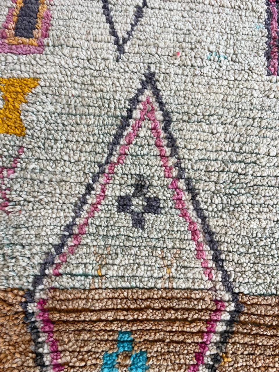 Close-up detail of a vintage Moroccan rug showcasing intricate patterns in beige, brown, and purple.