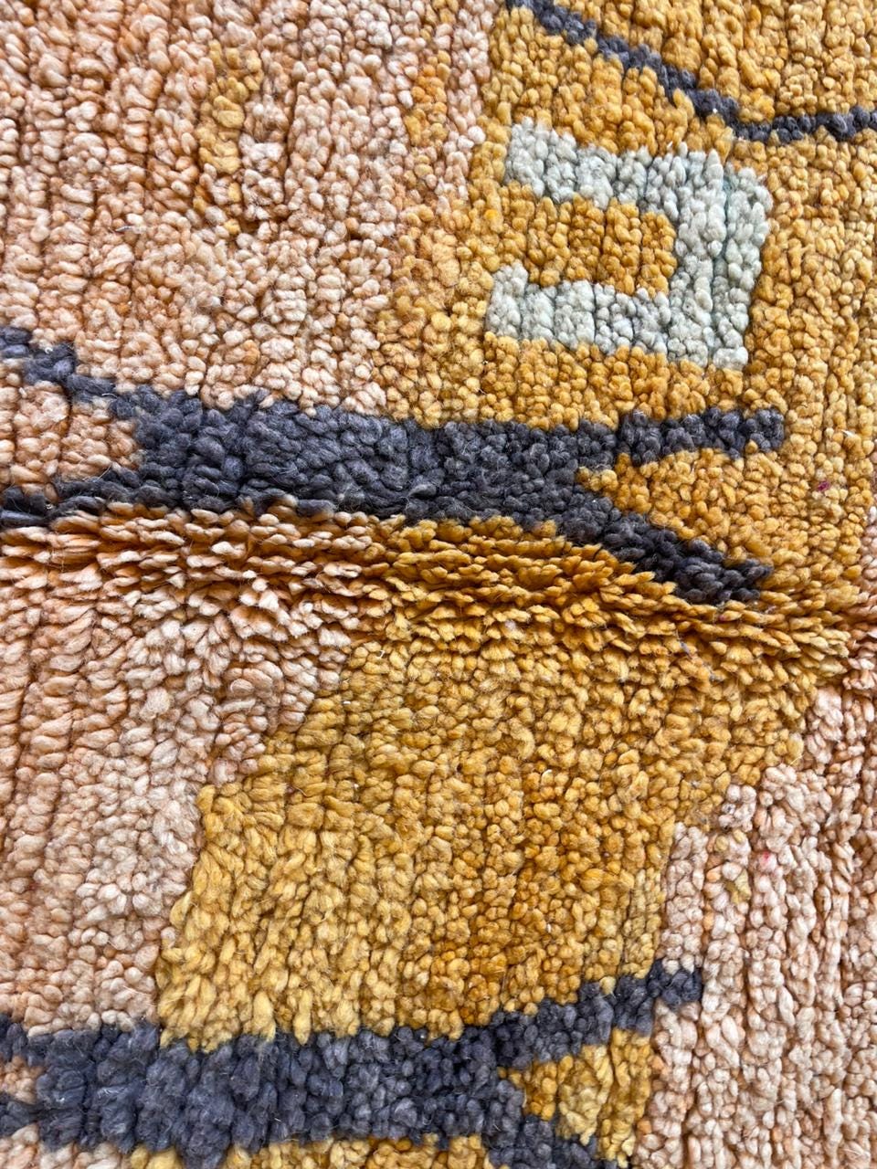 Detail shot of a woven textile featuring geometric patterns in brown, yellow, and black.