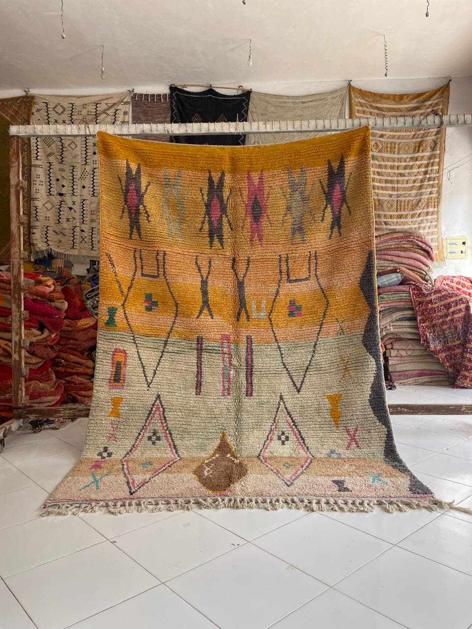 Lifestyle shot of a vintage Moroccan rug featuring geometric patterns in yellow, beige, and purple.