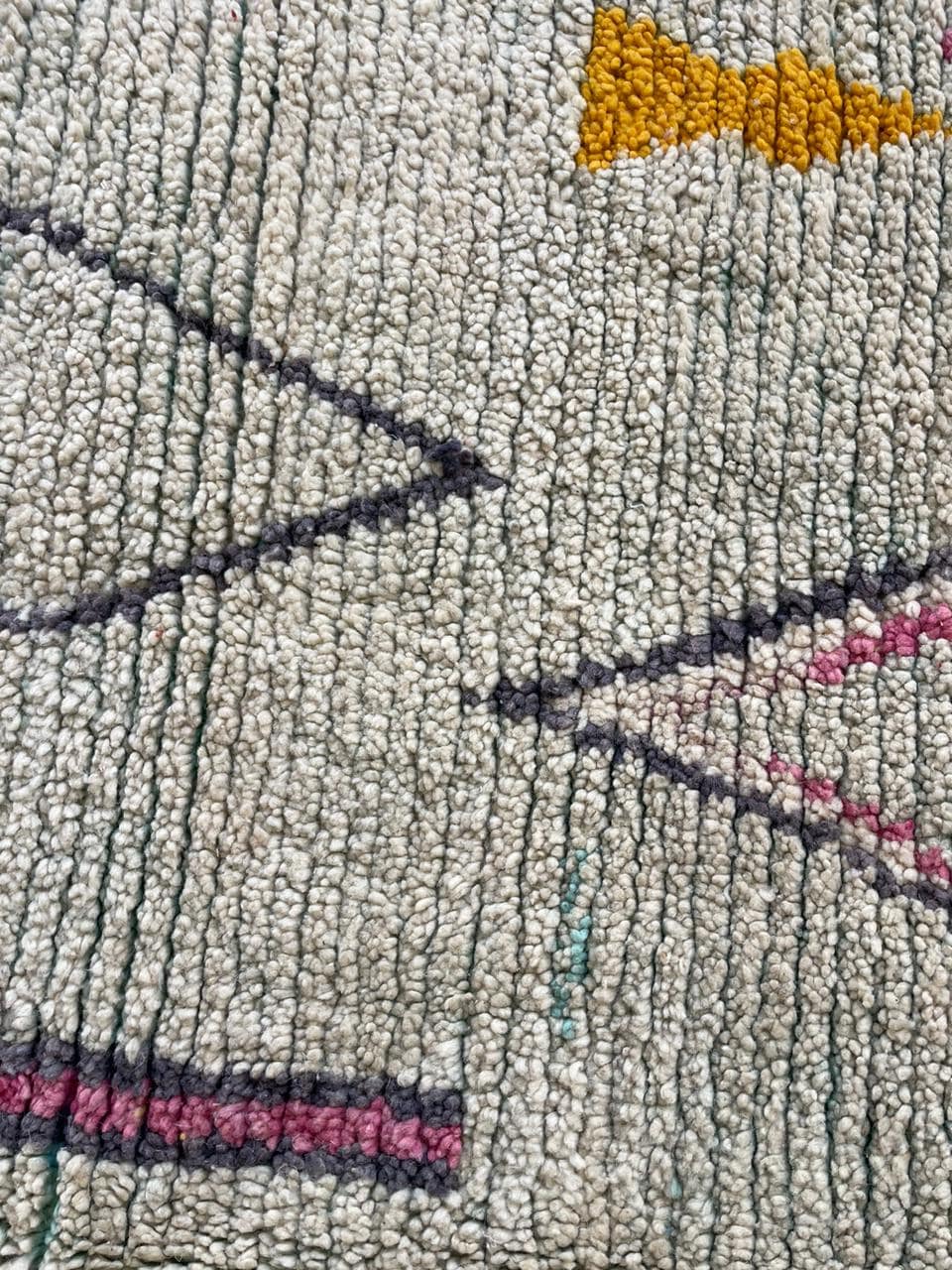 Close-up detail of a vintage Moroccan rug with geometric shapes in beige, black, and red.