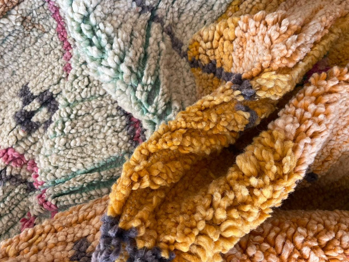 Detail shot of a woven textile showing colorful patterns in brown, yellow, and green.
