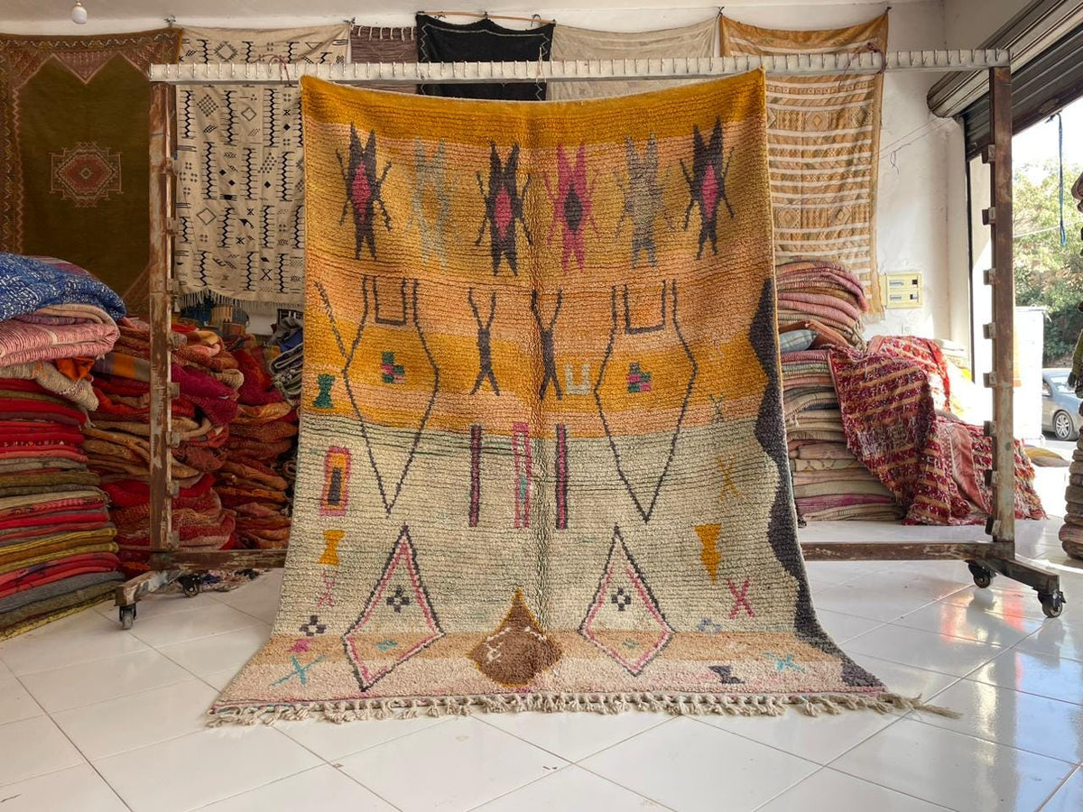 Lifestyle shot of a vintage Moroccan rug with intricate patterns in yellow, red, blue, and cream.