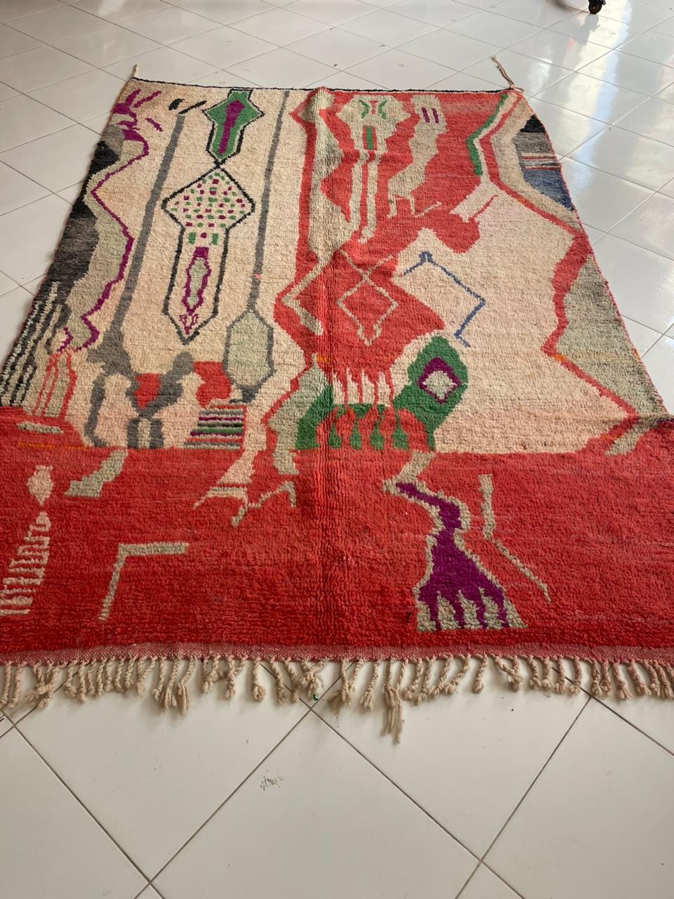 Lifestyle image of a vintage Moroccan rug with fringe edges and vibrant patterns.