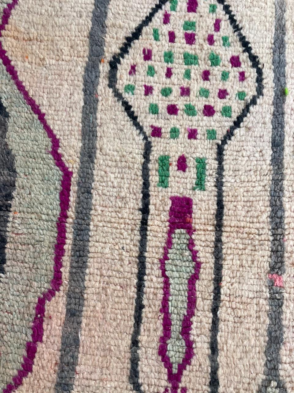 Front view of a large vintage Moroccan rug adorned with decorative motifs in red and green.