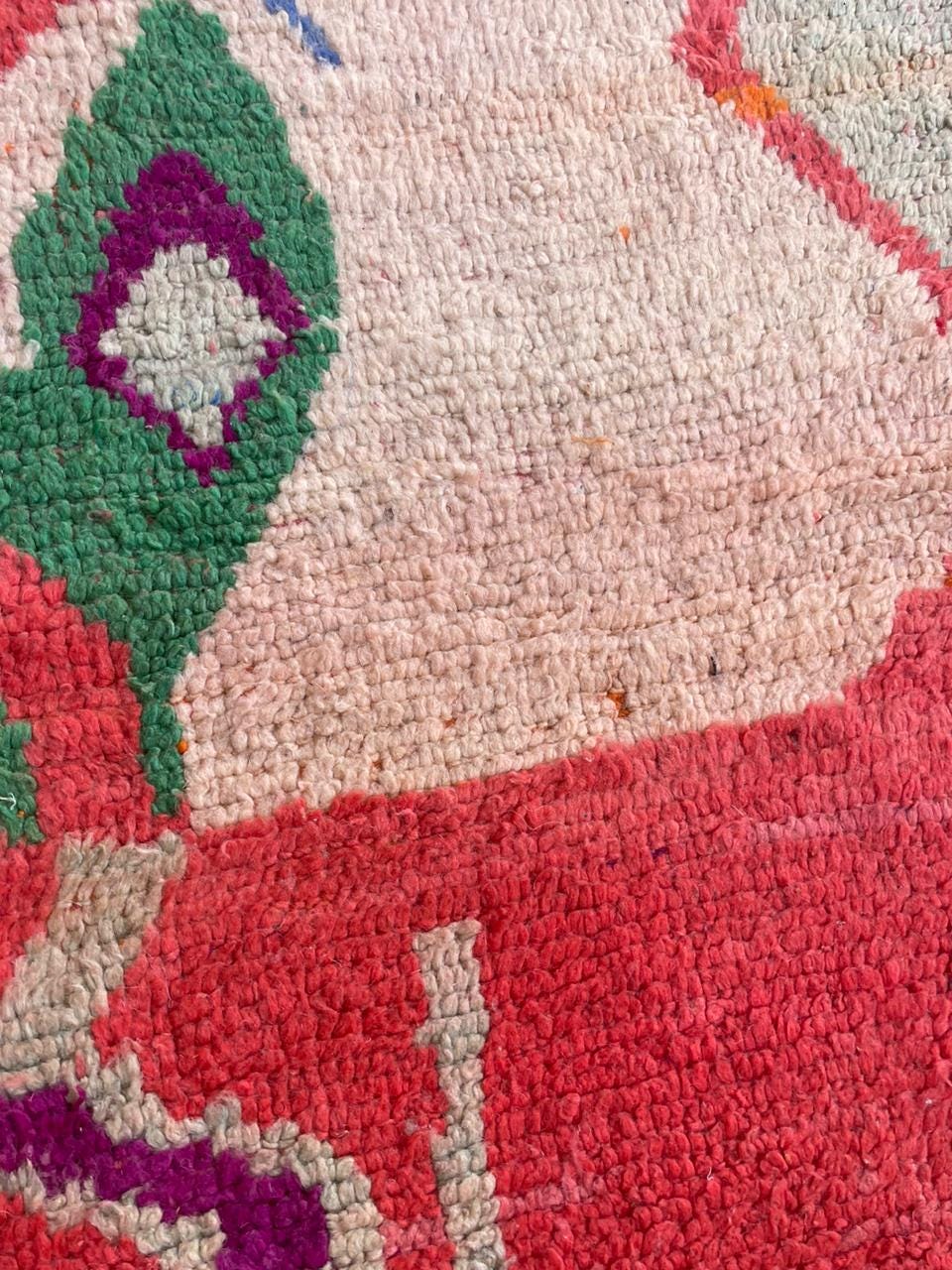 Close-up of a vintage Moroccan rug displaying a textured surface with colorful patterns.