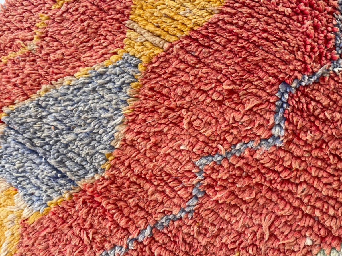 Detail view of a red vintage Moroccan rug featuring abstract patterns and rich colors.