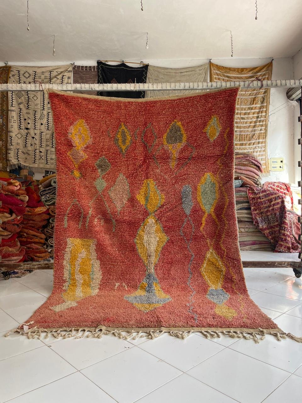 Lifestyle shot of a red vintage Moroccan rug featuring an abstract design and fringe edges.