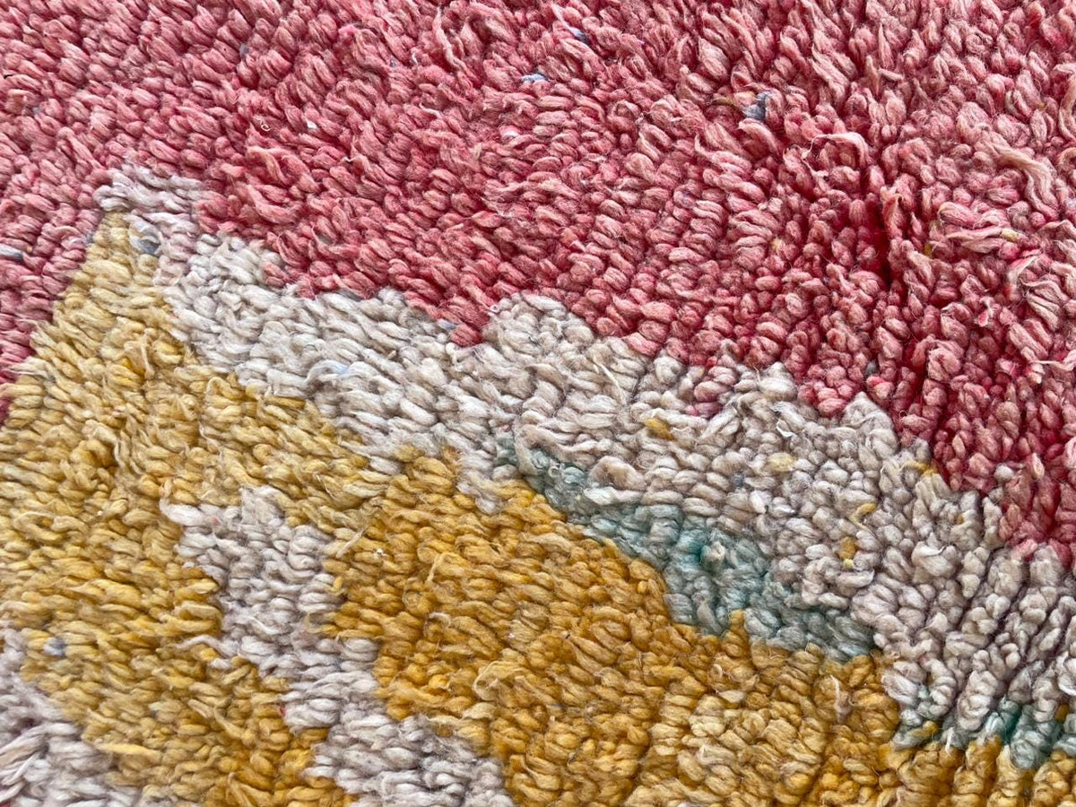 Close-up detail of the textured surface of a red vintage Moroccan rug with colorful patterns.