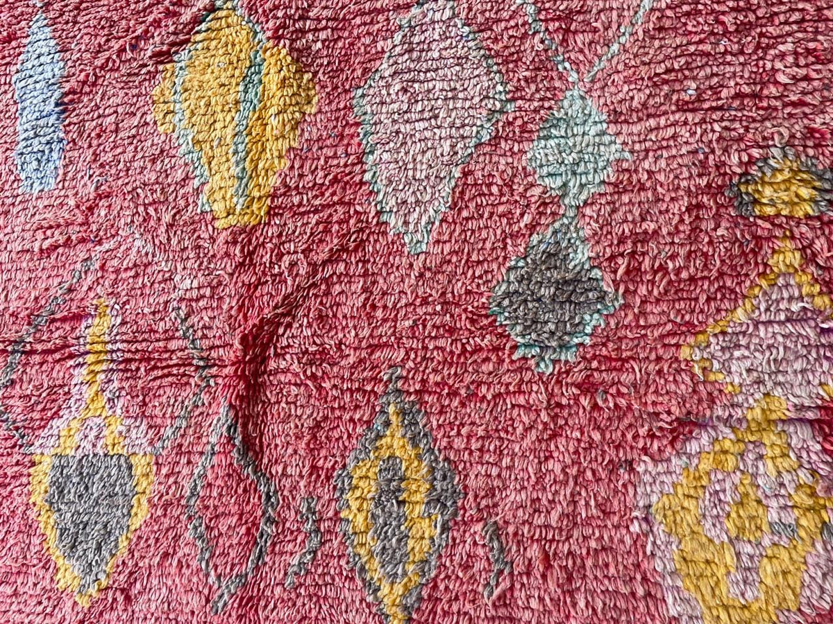 Detail shot of a red vintage Moroccan rug displaying abstract patterns and vibrant colors.