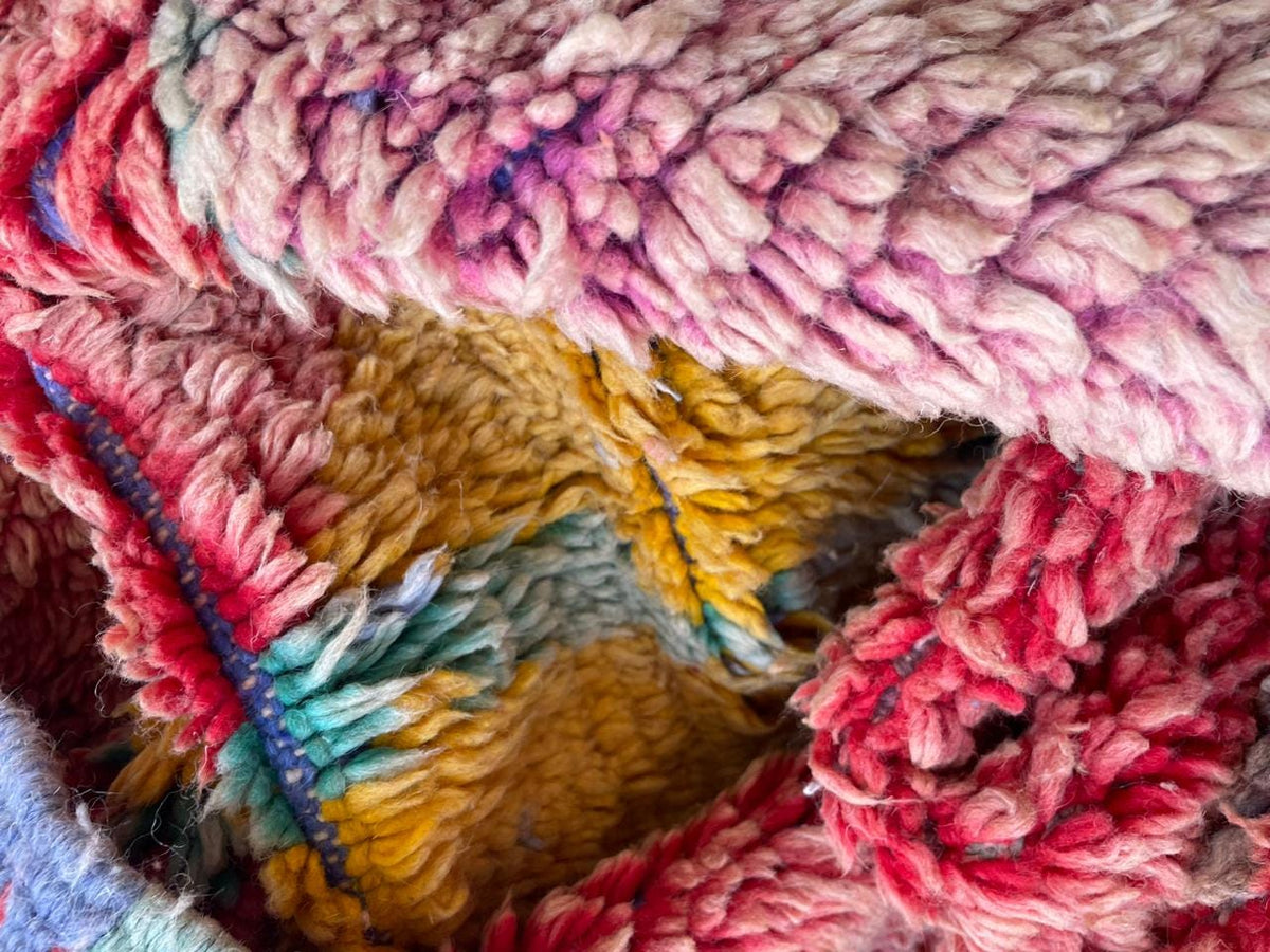 Close-up of a colorful woven rug with intricate patterns in red, yellow, and blue.