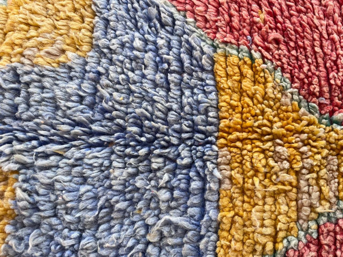 Close-up detail of a red vintage Moroccan rug with intricate abstract patterns.