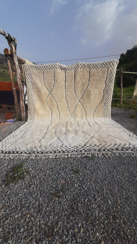 Lifestyle shot of a black and ivory geometric Moroccan rug on a natural background.