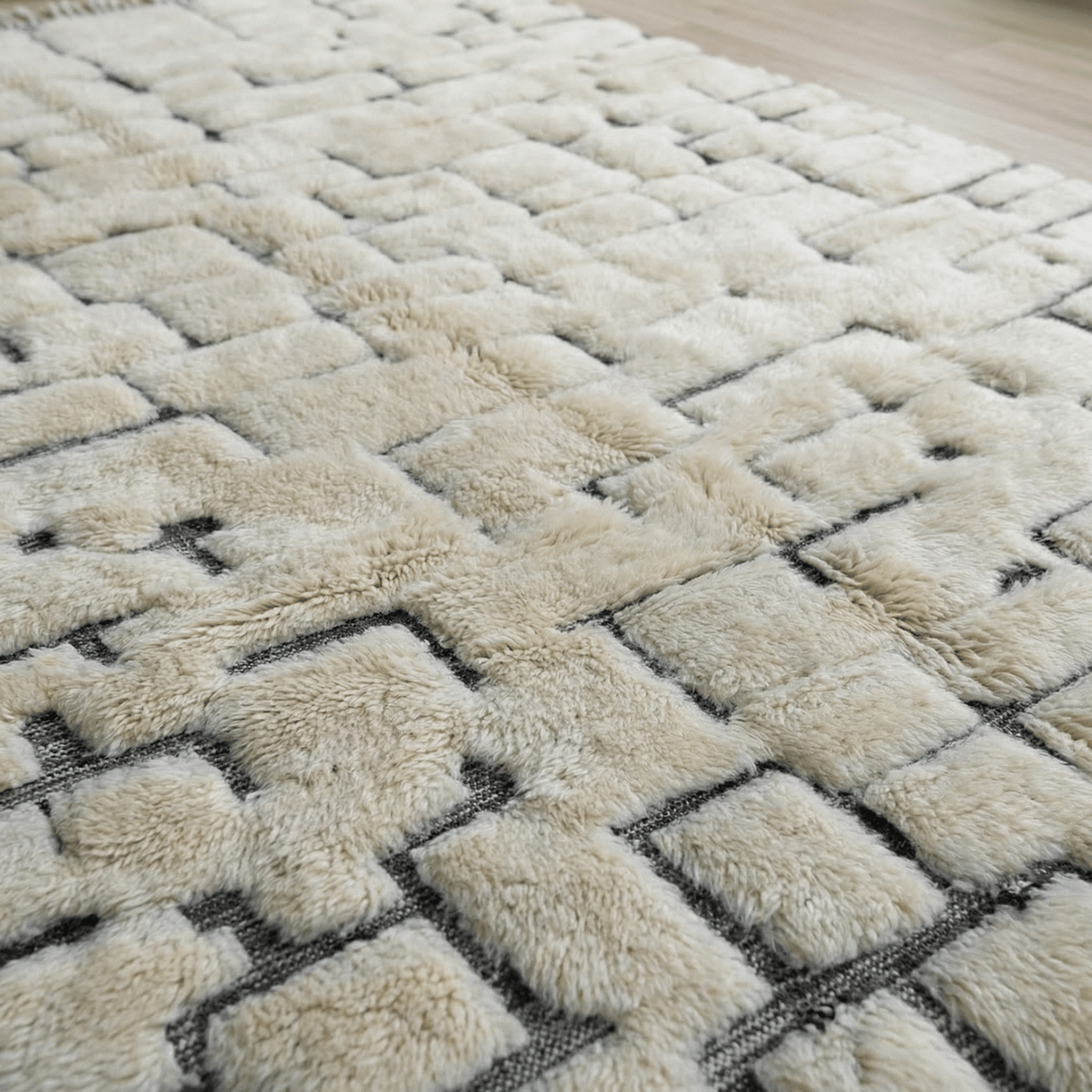 Detail close-up of the cream Moroccan rug displaying tufted texture and brick pattern.
