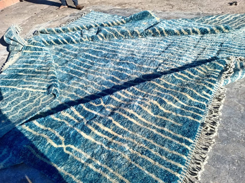 Detail view of a turquoise Moroccan rug featuring a striped pattern and textured surface.
