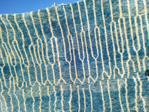 Detail close-up of a turquoise Moroccan rug featuring a geometric pattern and textured surface.