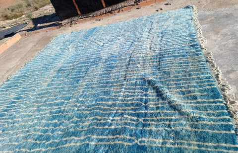 Detail shot of a turquoise Moroccan rug with a geometric design and textured surface.