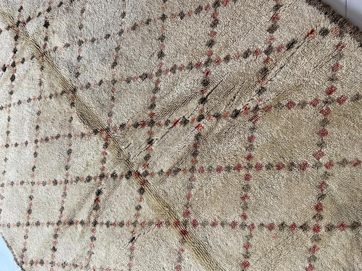 Close-up detail of a geometric patterned Moroccan rug in beige, black, and red.