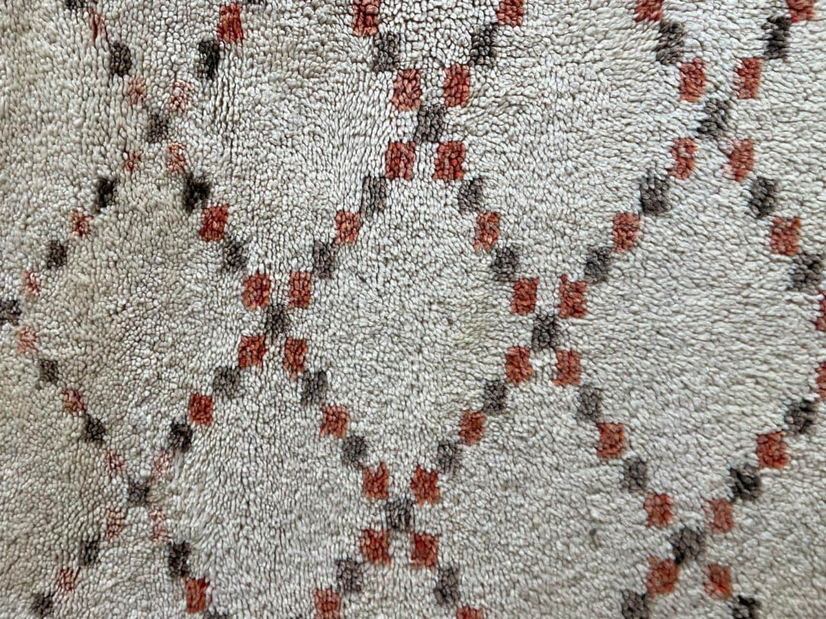Close-up detail of a diamond patterned Moroccan rug in white, black, and red.
