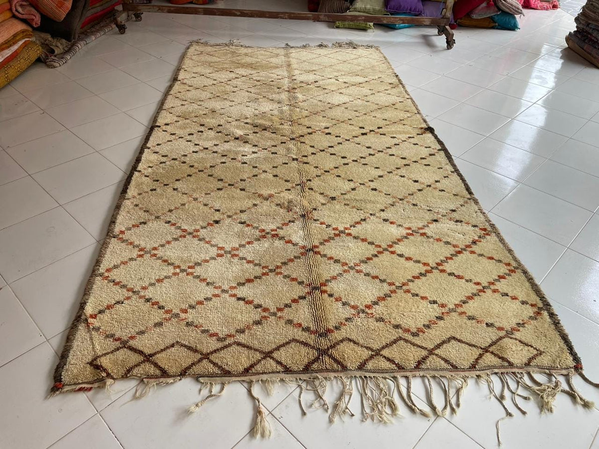 Front view of a beige and brown diamond patterned Moroccan rug with fringe edges.