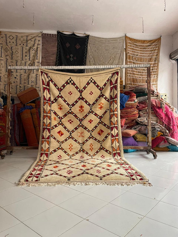 Lifestyle shot of a vintage Moroccan rug featuring geometric patterns in beige, red, and black.