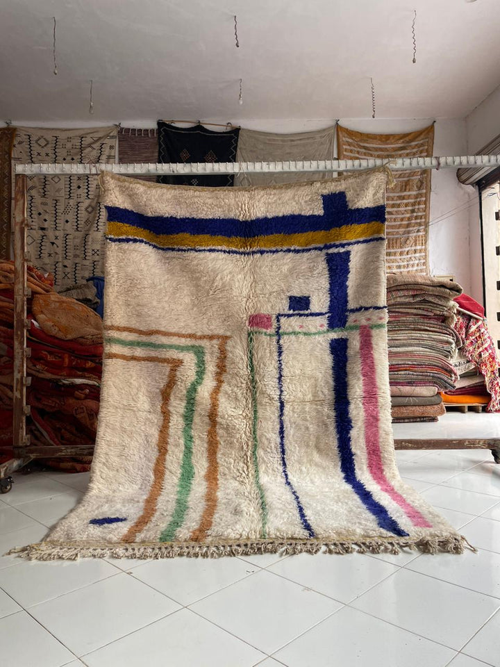Lifestyle shot of a vintage Moroccan rug with geometric patterns in cream, blue, and red.