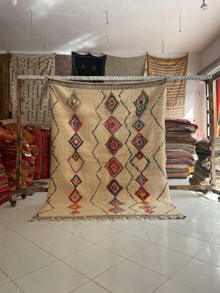 Lifestyle shot of a vintage Moroccan rug featuring beige, red, and blue tribal patterns.
