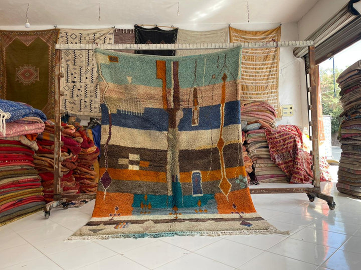 Lifestyle shot of a vintage Moroccan rug featuring geometric patterns in blue and orange.