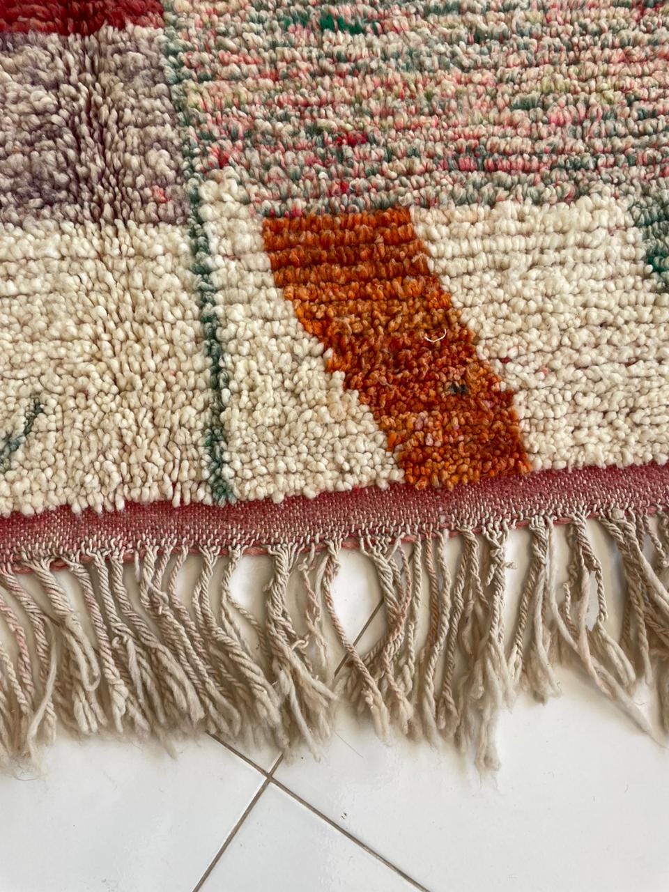 Close-up of a vintage rug highlighting its fringe and textured pattern.