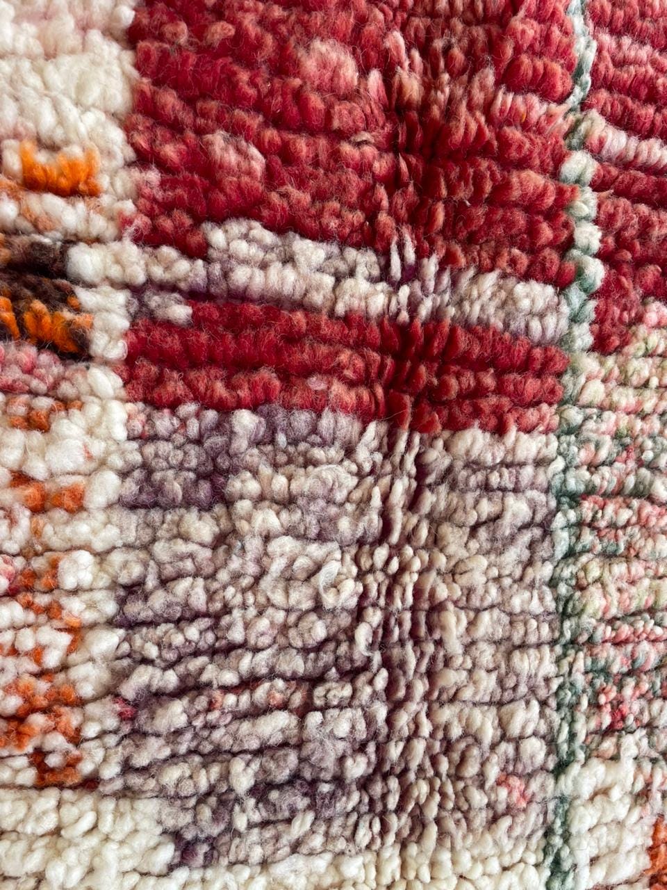 Front view of a large vintage rug featuring colorful patterns in red, cream, and green.