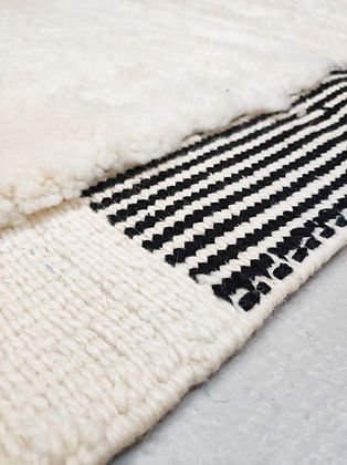 Close-up detail of a white and black tufted rug featuring a striped pattern