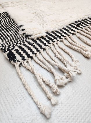 Front view of a white and black tufted rug featuring a geometric design on a solid background