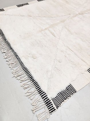 Close-up detail of the edge of a white and black tufted rug showing fringe and texture