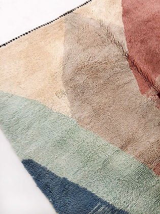 Detail close-up of a wool area rug showcasing an abstract design in beige, green, brown, and red.